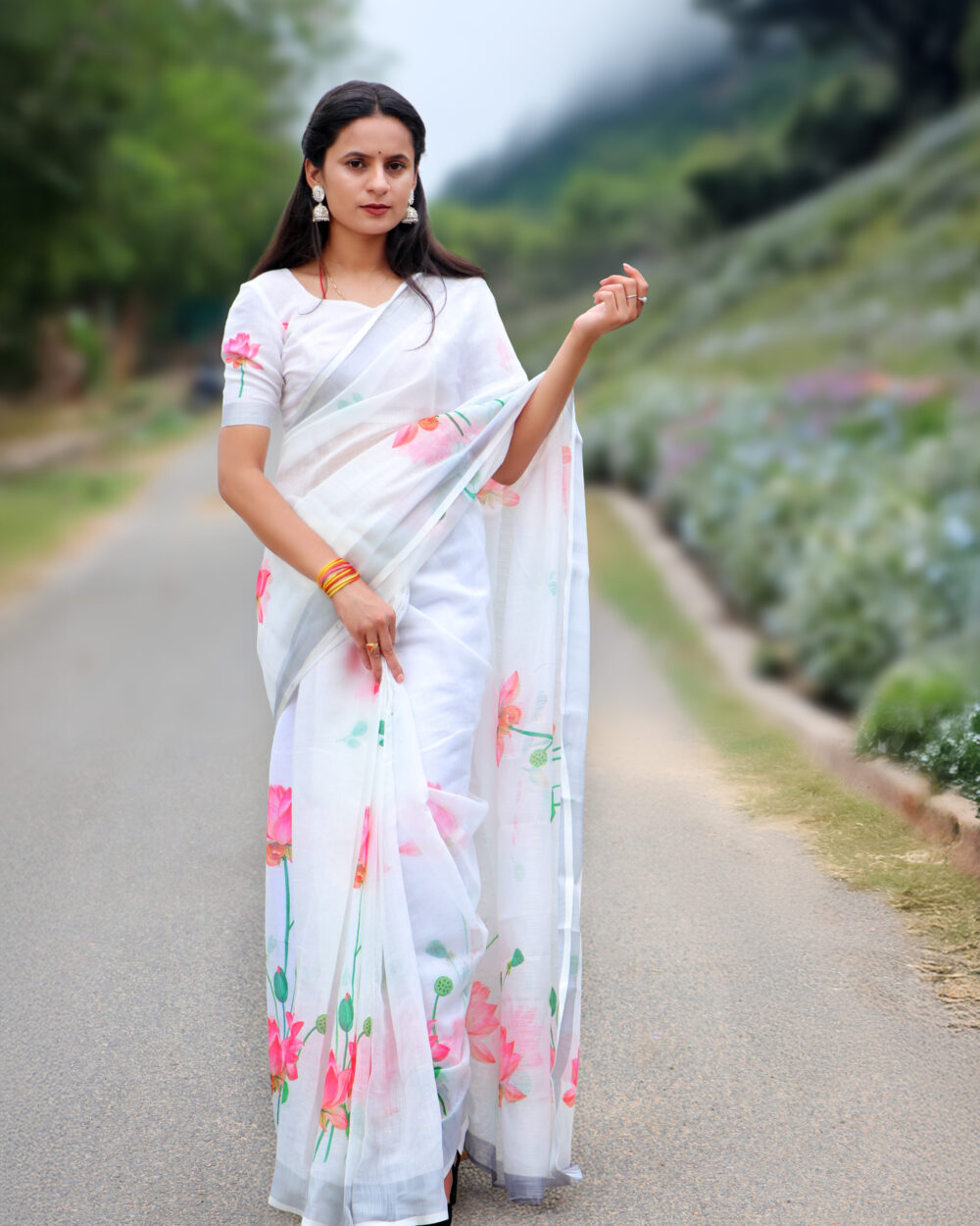 Woman wearing white printed saree with pink lotus design, styled for office or farewell look
