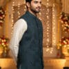Close-up of a man wearing a teal textured Nehru jacket with a mandarin collar, bronze buttons, and a pocket square; ideal for formal ethnic and festive attire.