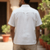 Men's white short-sleeve shirt with black floral embroidery, camp collar, and relaxed fit – front, close-up, and back view.